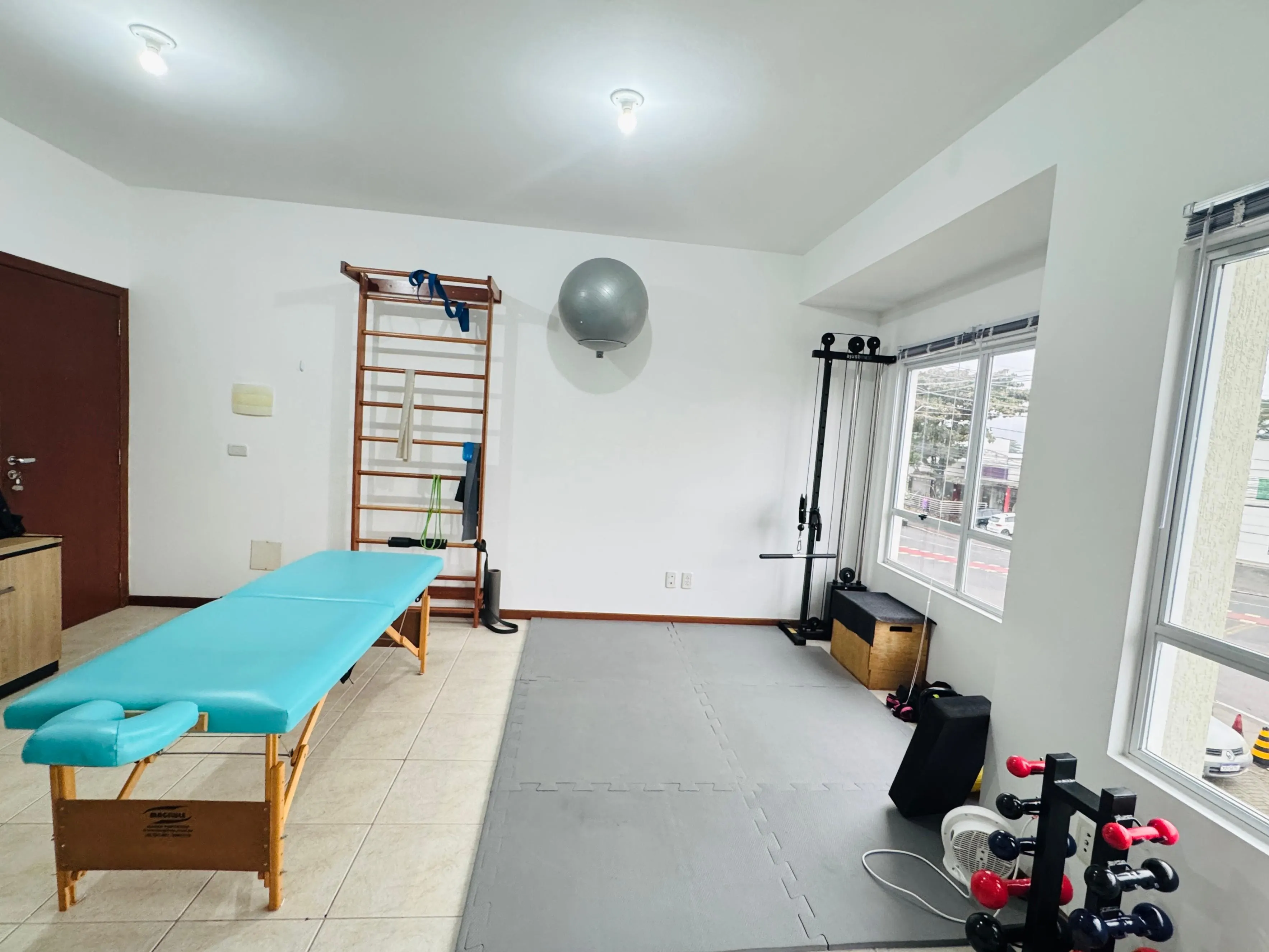 Sala de atendimento na Lins Fisioterapia, com maca, barra de parede e equipamentos de exercício